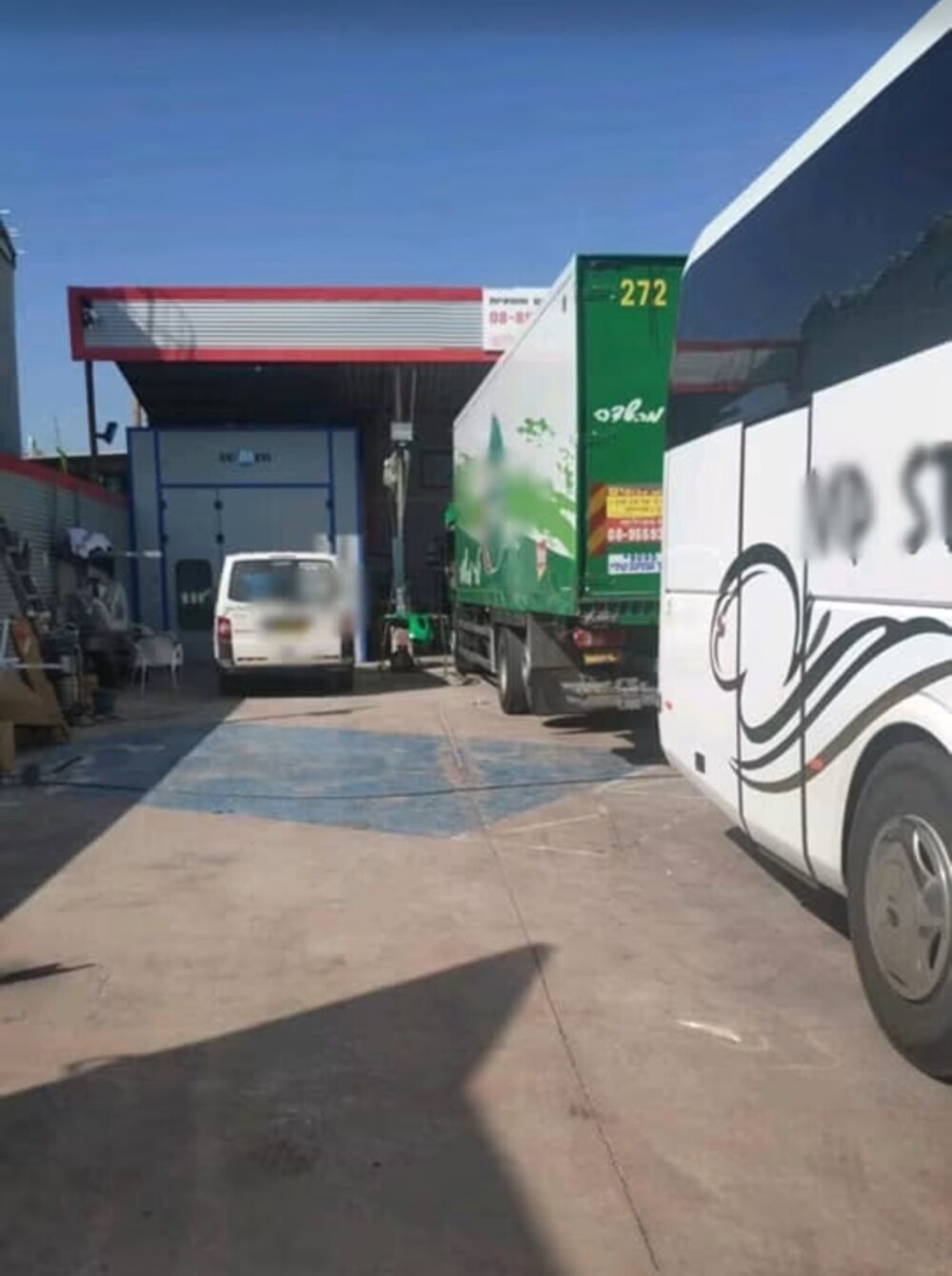 חצר מוסך צרויה ובה משאית ואוטובוס בטיפול